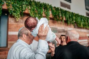 מוהל מחזיק את התינוק אחרי טקס ברית